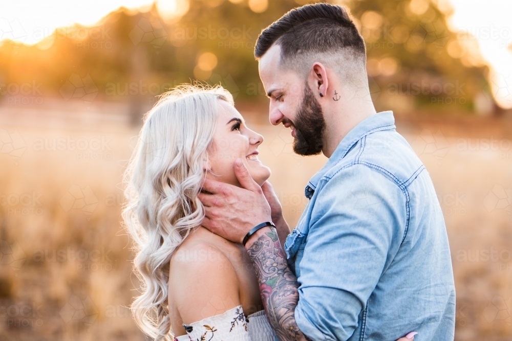 Young couple looking at each other smiling man holding woman's face - Australian Stock Image