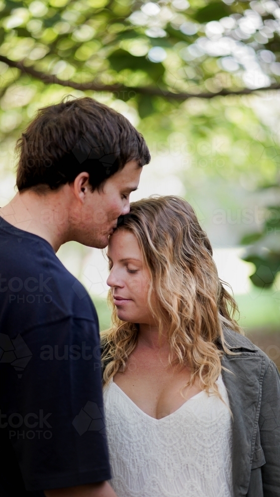 Young couple, man kissing woman's head - Australian Stock Image