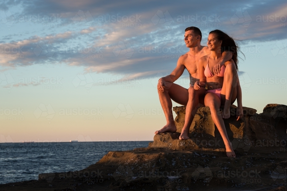 Young couple on the ocean rocks at sunrise - Australian Stock Image