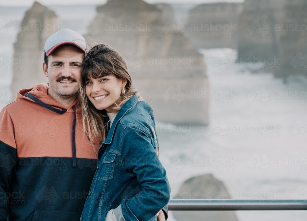 Young couple pose for photo at the twelve apostles. - Australian Stock Image