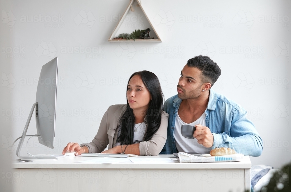 Young couple searching online together over breakfast - Australian Stock Image