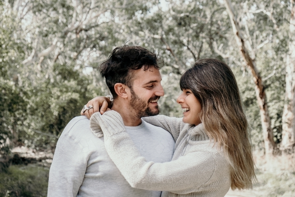 Young couple smiling at each other outdoors. - Australian Stock Image