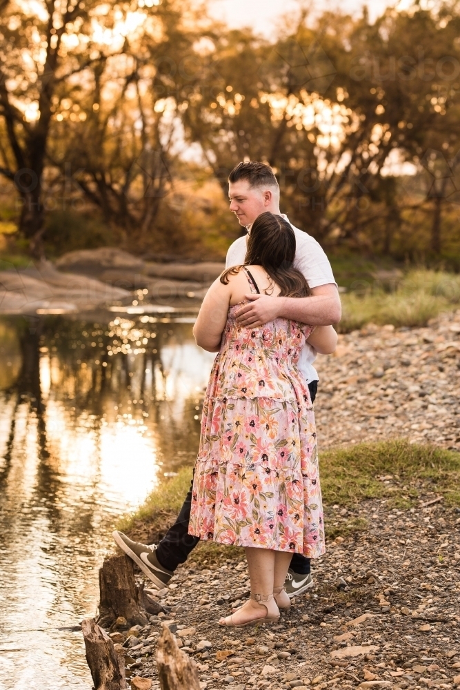 Young couple standing near water woman looking up at man - Australian Stock Image