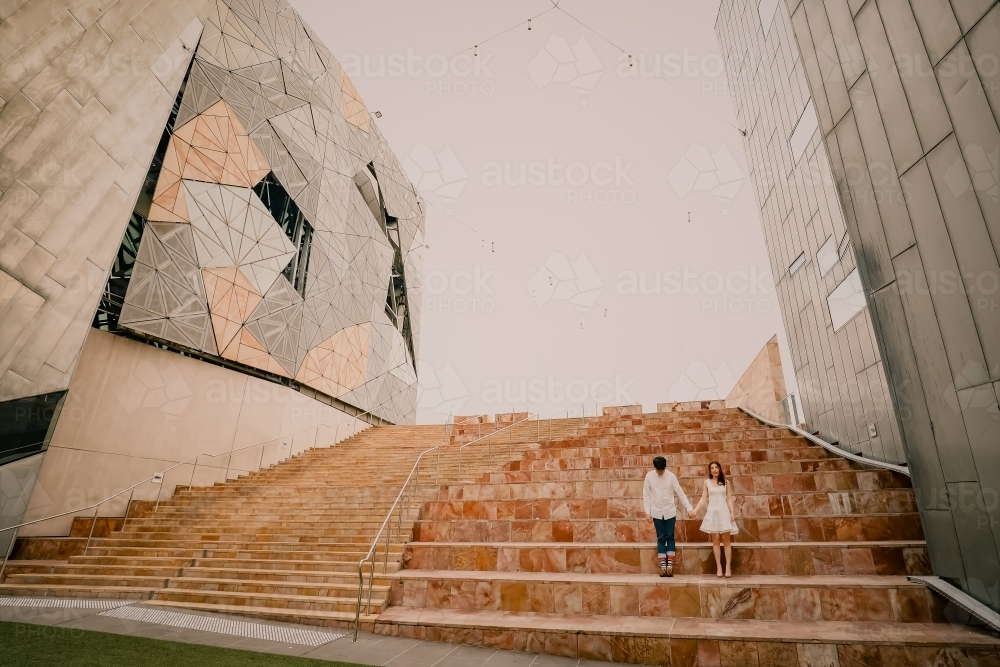 Young couple standing together on steps at Federation Square - Australian Stock Image