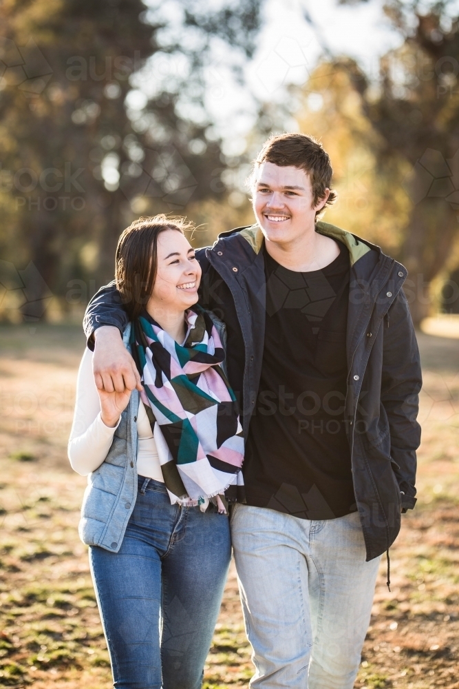 Young couple walking together holding hands looking away smiling - Australian Stock Image