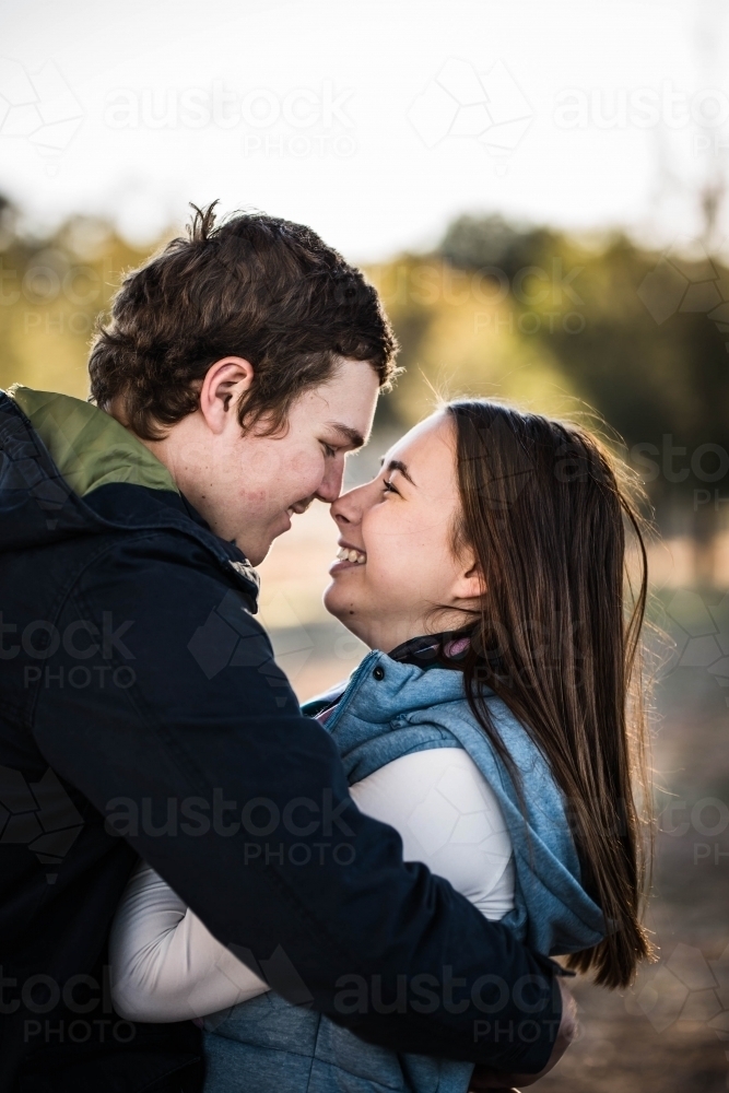 Young couple wrapped in each other's arms noses touching laughing - Australian Stock Image