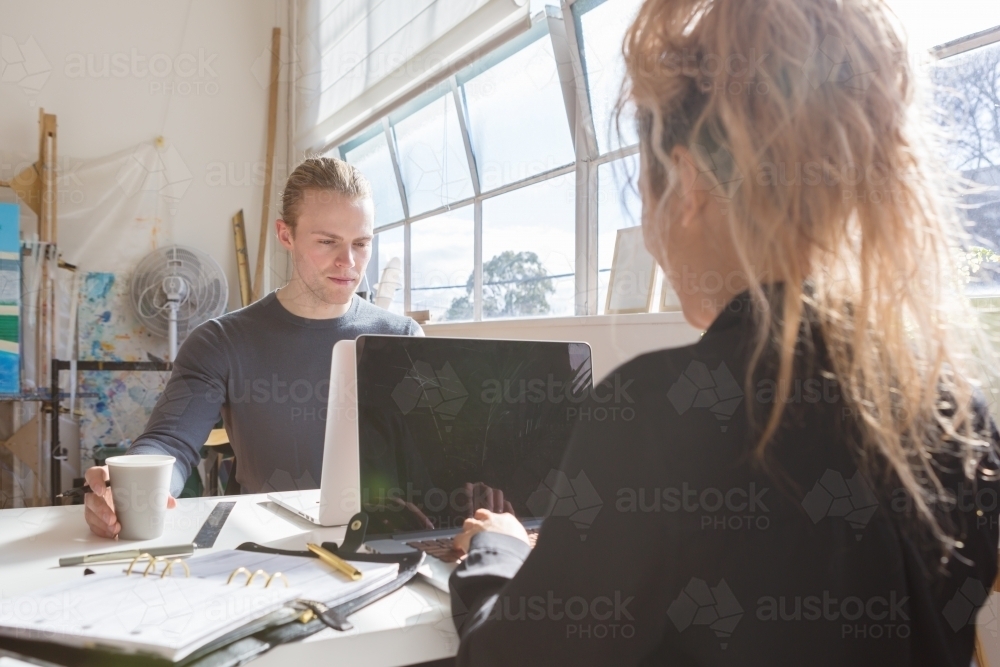 Young creative guy and girl sharing a co-working space - Australian Stock Image