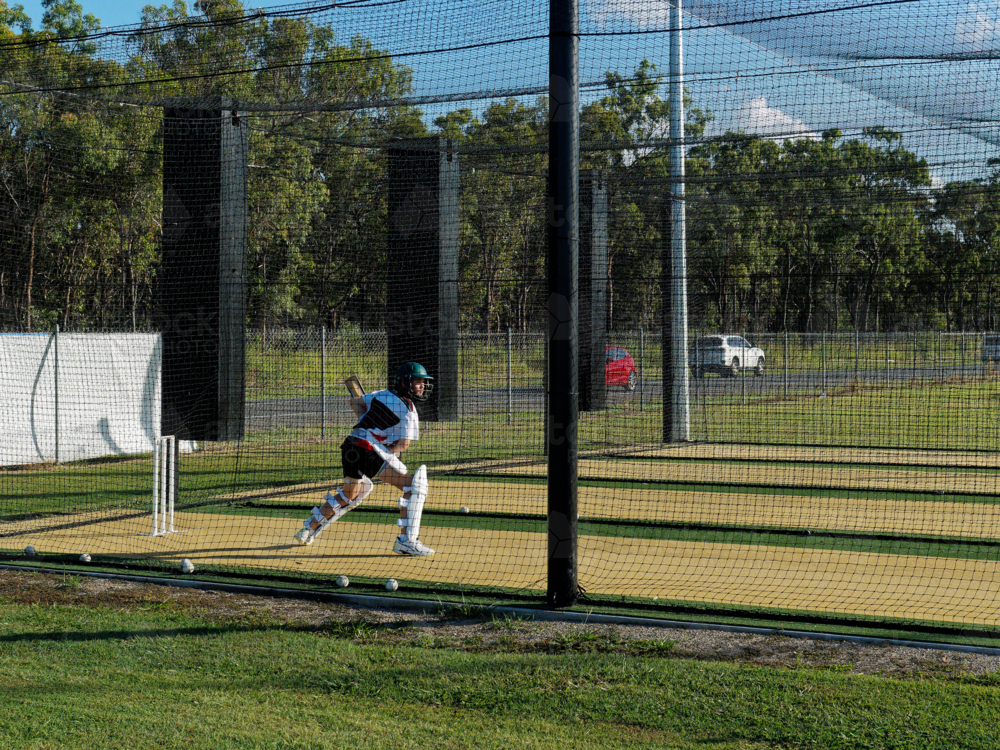 Young cricket batter practising running drills inside training nets - Australian Stock Image