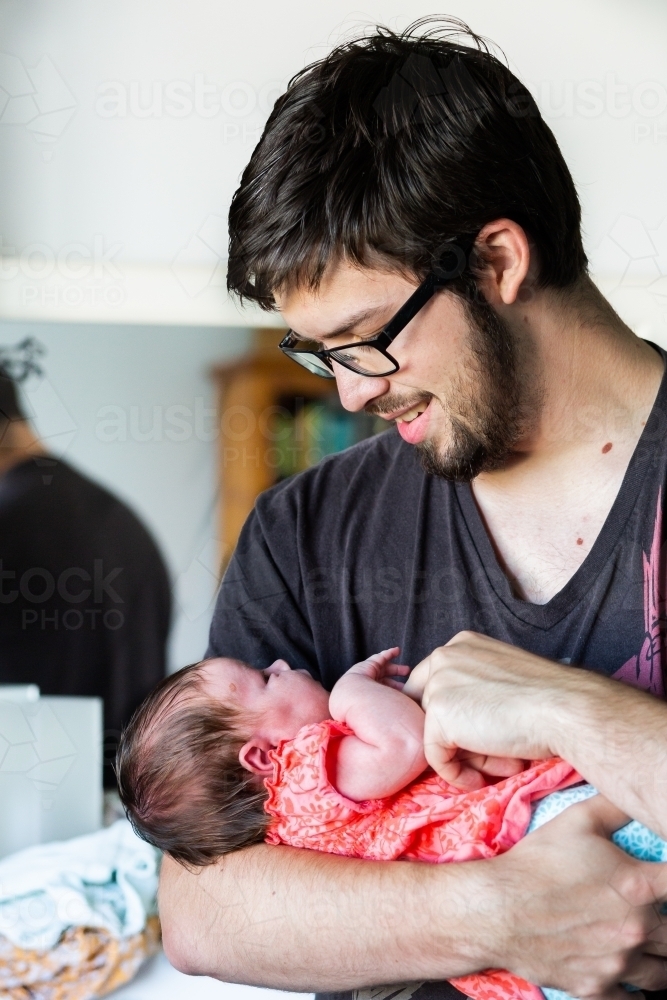 Young dad with baby girl daughter in arms - parent with newborn - Australian Stock Image