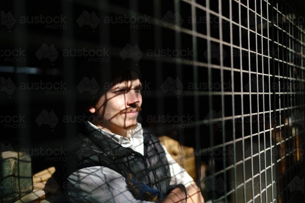 Young Disabled Man Looking out Through Wire Grate - Australian Stock Image