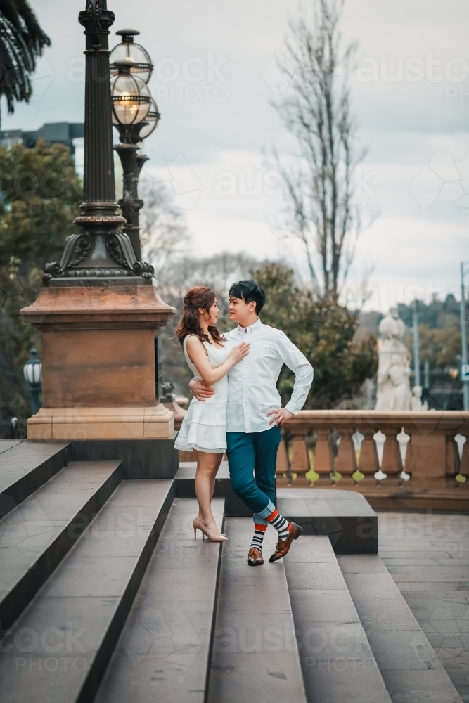 Young engaged couple embracing on the steps of the Old Treasury Building in Melbourne - Australian Stock Image
