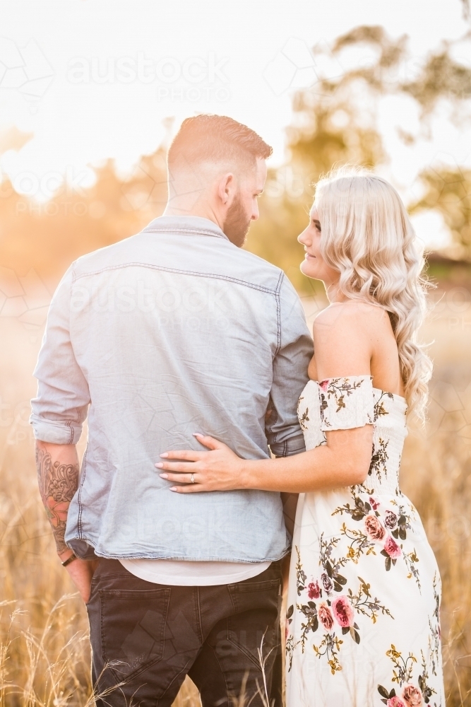 Young engaged couple standing looking at each other - Australian Stock Image