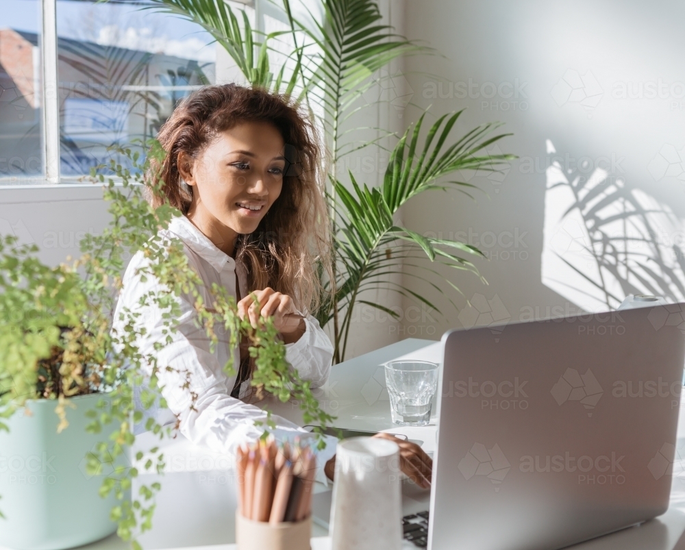 Young executive working in an office with indoor plants - Australian Stock Image