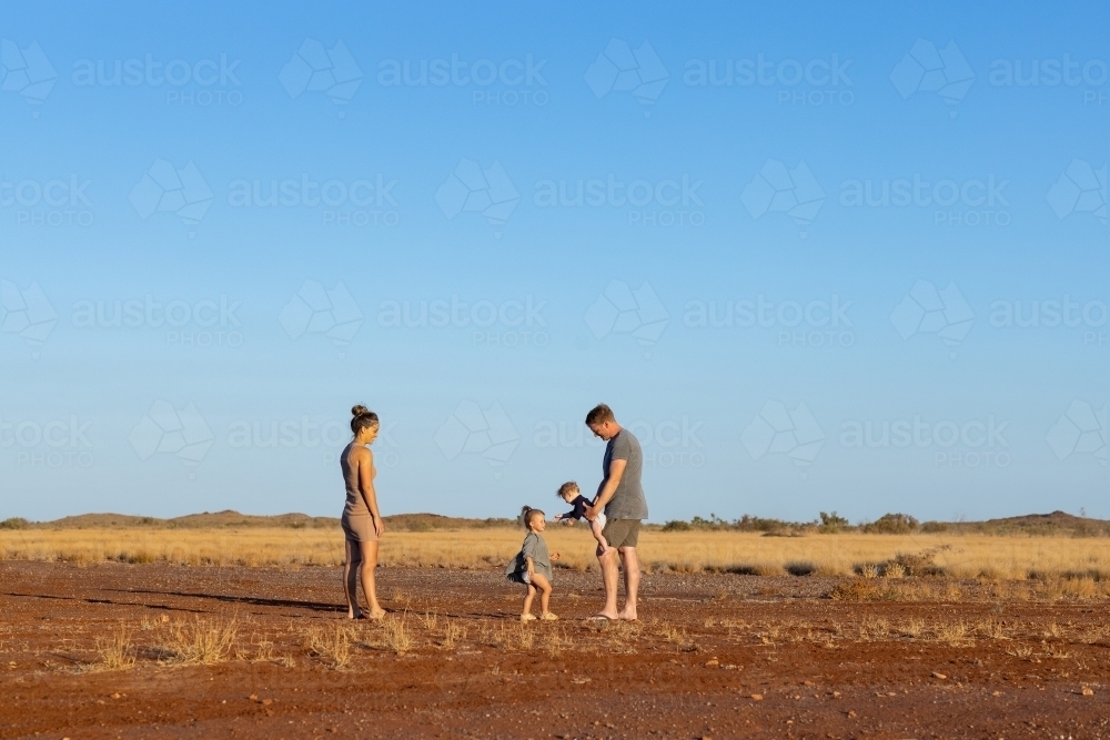 young family of four in the Pilbara landscape with big blue sky - Australian Stock Image