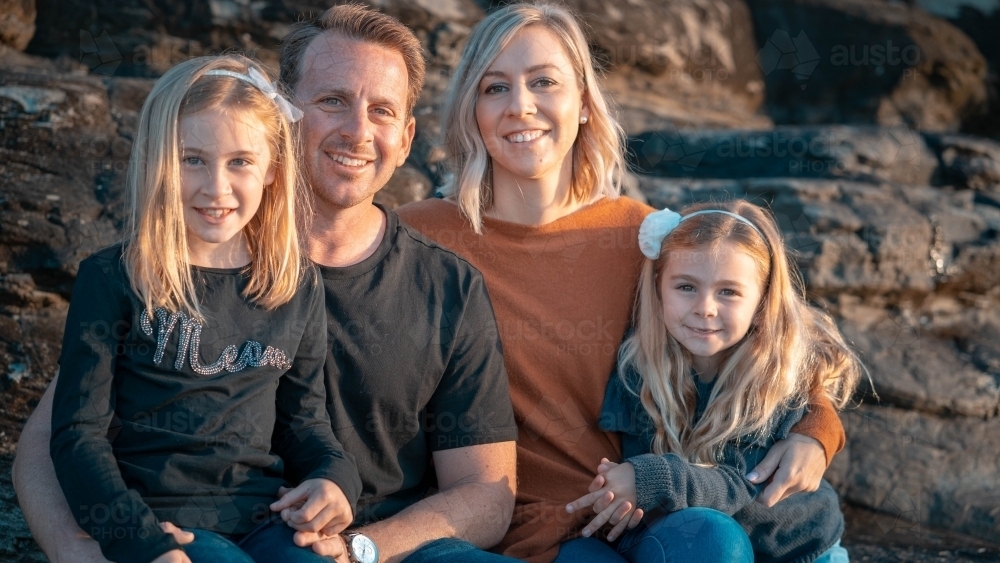 Young family of four portrait at sunrise on beach - Australian Stock Image