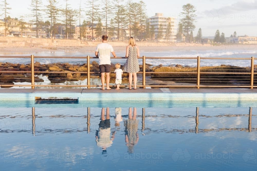 Young family of three at the ocean pool overlooking the beach - Australian Stock Image