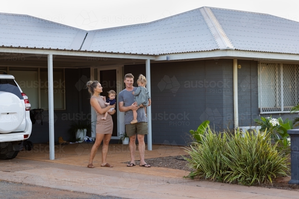 young family outside their modest home - Australian Stock Image