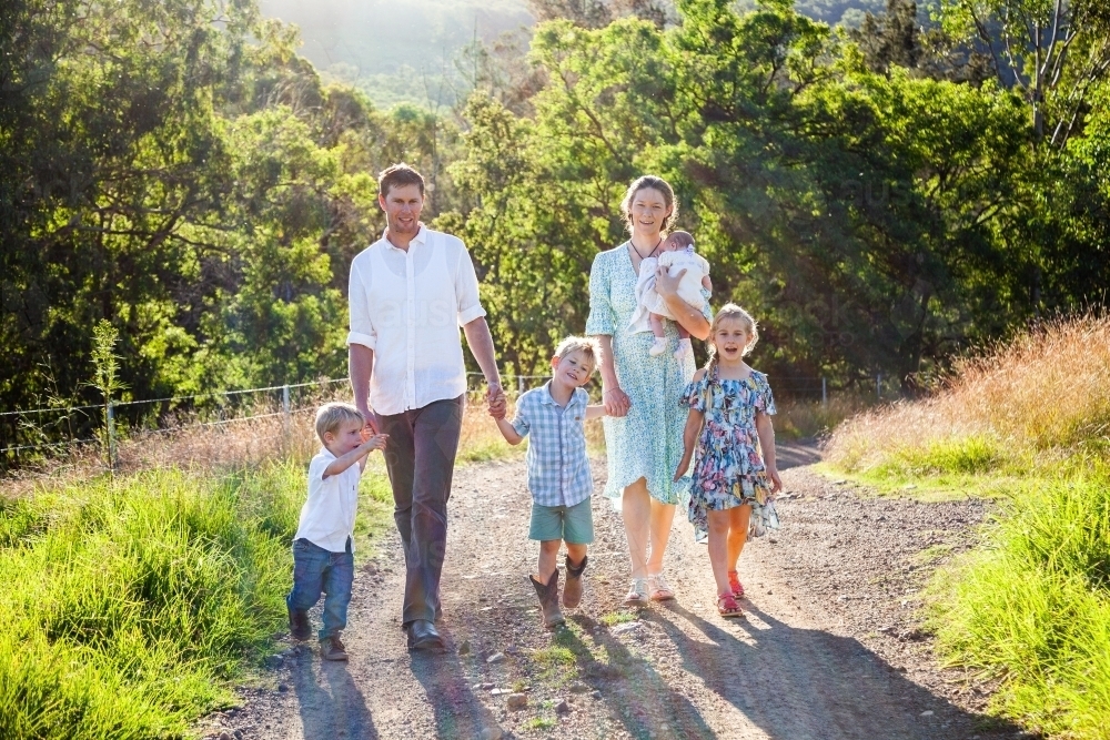 Young family walking down their driveway on a farm - Australian Stock Image