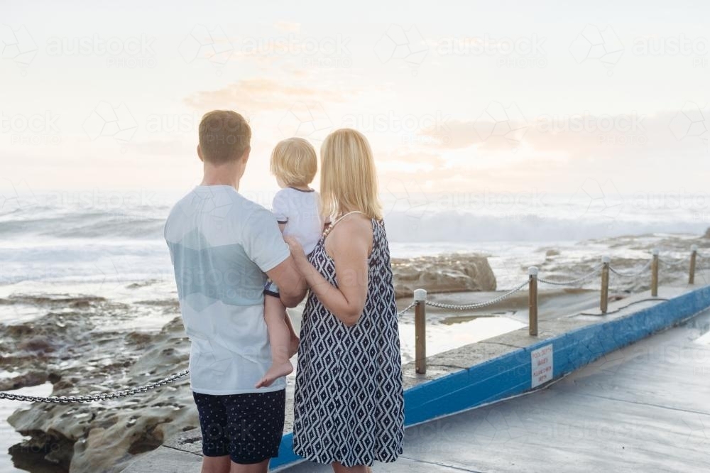 Young family watching the sunrise at the beach - Australian Stock Image