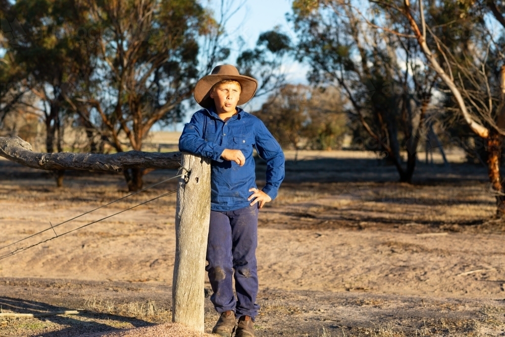 young farm boy leaning on a fence post - Australian Stock Image