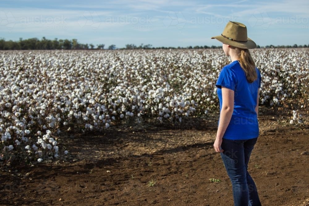 Young farm kid standing near a paddock of cotton - Australian Stock Image