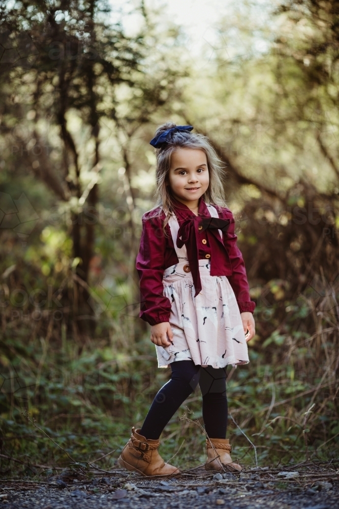 Young fashionable girl standing in bush setting smiling at camera - Australian Stock Image