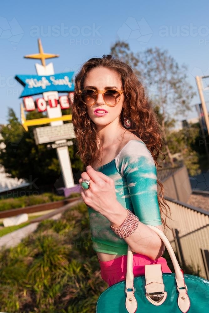 Young fashionable woman with blue handbag, looking to camera - Australian Stock Image