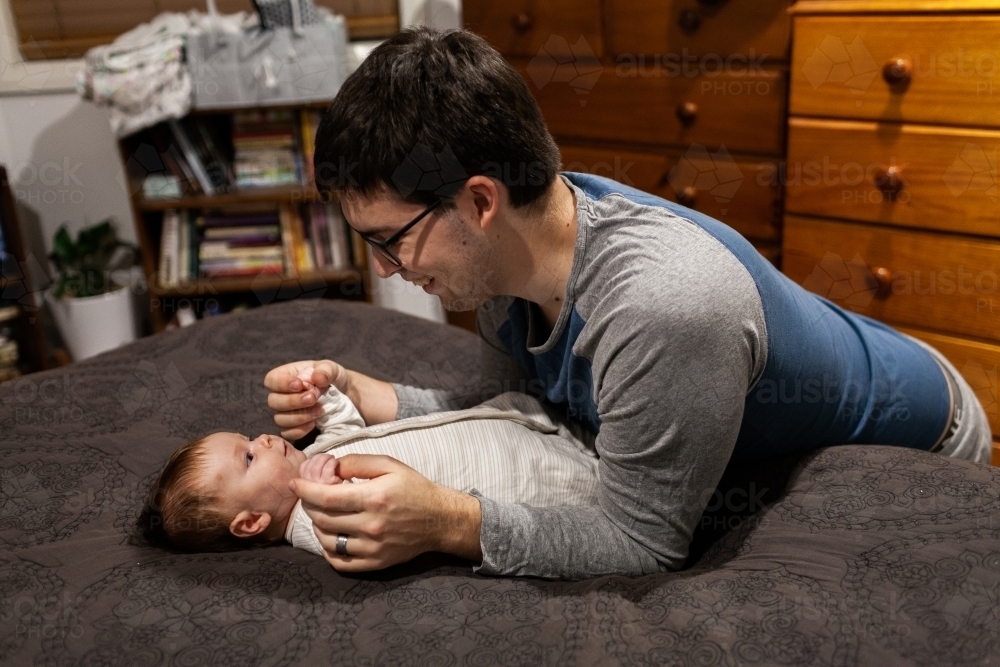 Young father playing with baby before bed in bedroom - Australian Stock Image