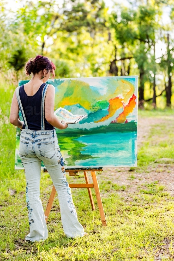 Image of Young female artist with sketchbook reference book working on ...