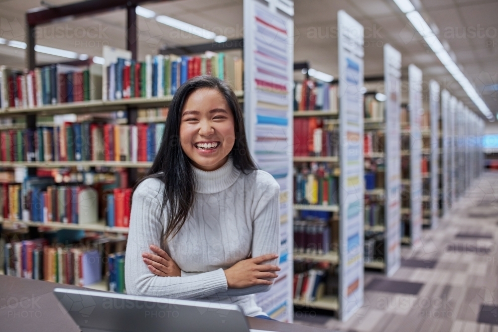 Young female Asian student working on her laptop at university library - Australian Stock Image