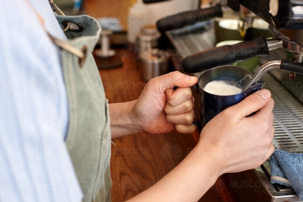 Young female barista preparing coffee with coffee machine - Australian Stock Image