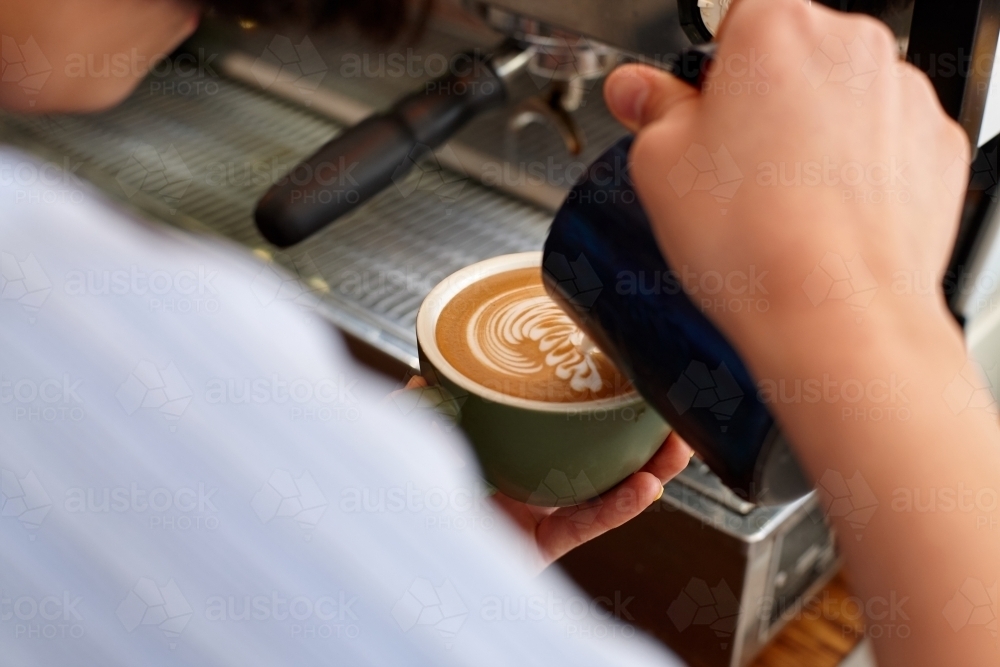 Young female barista preparing coffee with coffee machine - Australian Stock Image