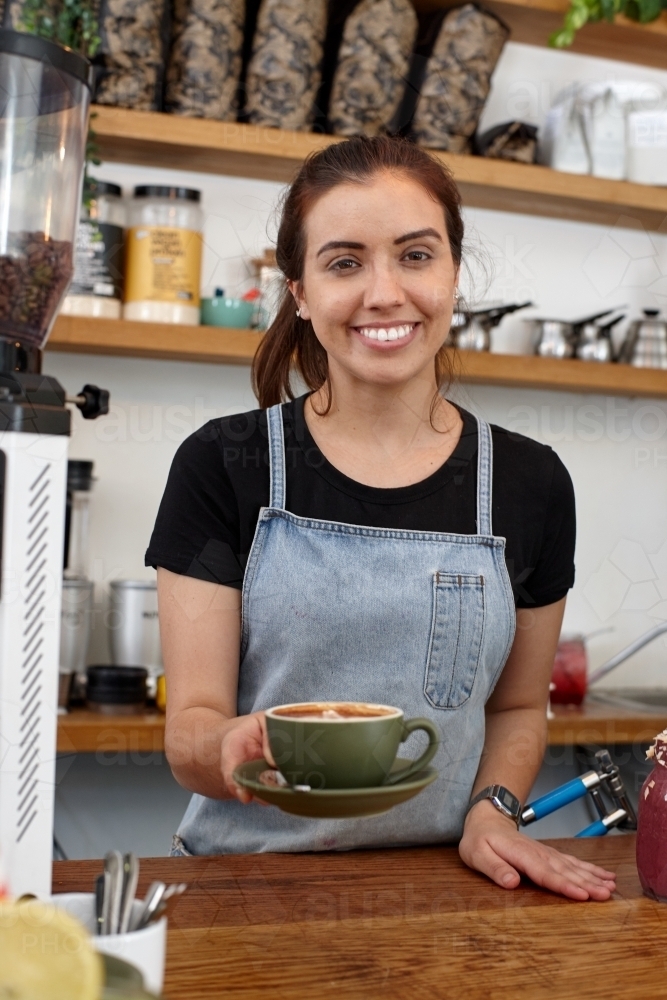 Image of Young female barista serving a fresh hot coffee - Austockphoto