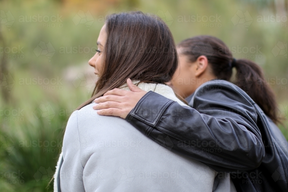 Young female couple sitting in an outdoor setting from behind - Australian Stock Image