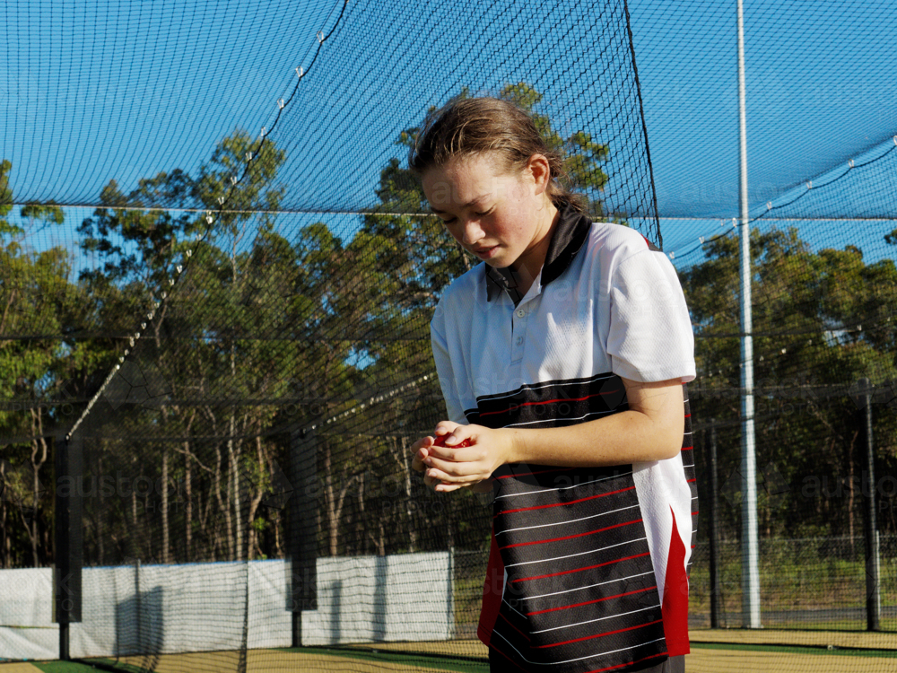 Young female cricketer practicing in the nets holding a cricket ball - Australian Stock Image