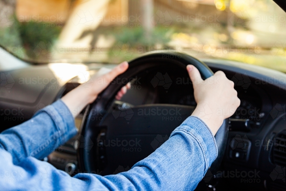 Young female driver with two hands on the steering wheel - Australian Stock Image
