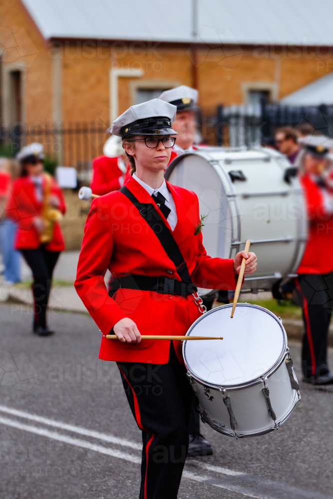 Young female drummer playing in local band during ANZAC day parade march - Australian Stock Image