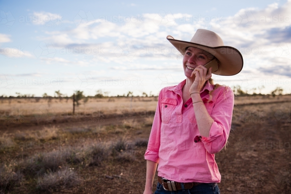 Young female farmer holding phone to her ear - Australian Stock Image