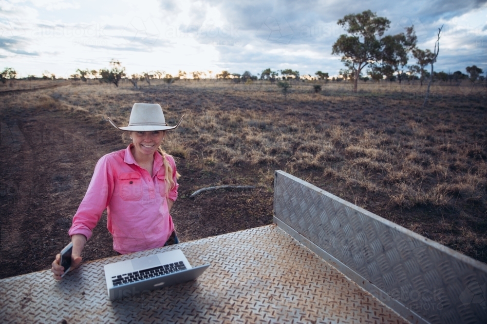 Young female farmer with communication devices - Australian Stock Image