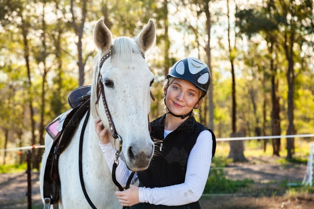 Young female horsewoman with her horse wearing a riding helmet for safety - Australian Stock Image