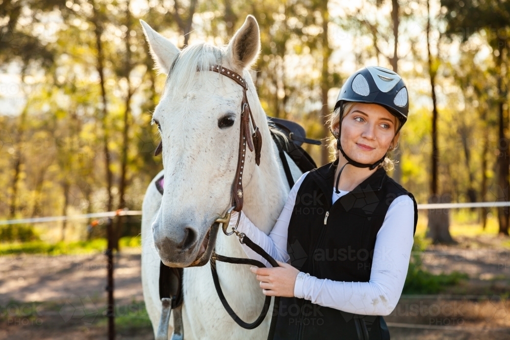 Young female horsewoman with her horse wearing a riding helmet for safety - Australian Stock Image
