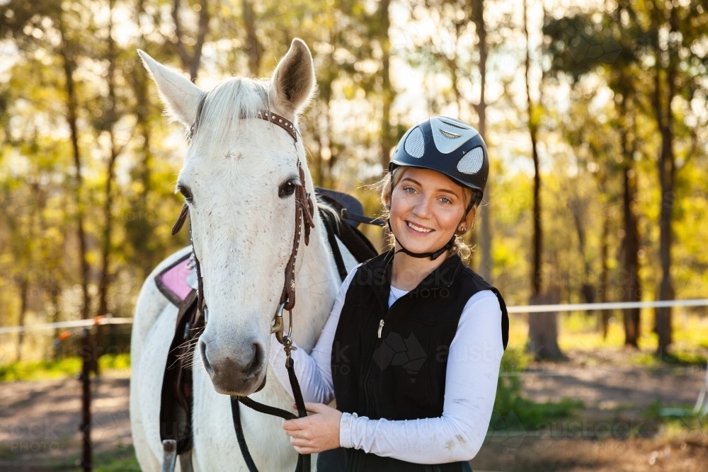 Young female horsewoman with her horse wearing a riding helmet for safety - Australian Stock Image