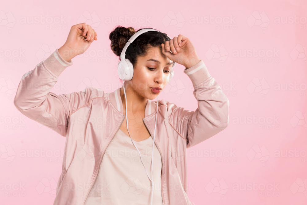 young female in pink dancing with headphones in studio - Australian Stock Image