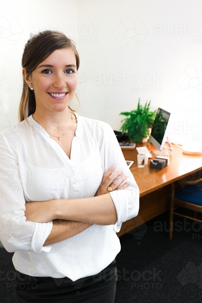 Image of Young female office worker standing with colleague sitting at a  computer in the background - Austockphoto