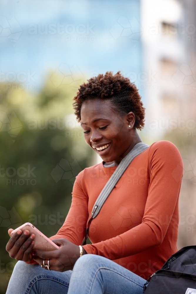 Young female photographer checking mobile phone messages in city - Australian Stock Image