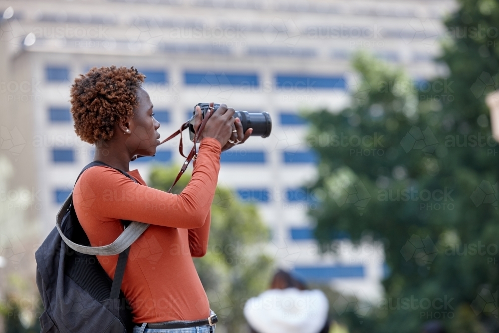 Young female photographer taking a picture in the city with dslr - Australian Stock Image