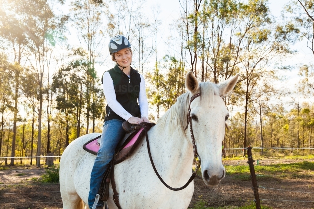 Young female rider on her horse wearing a riding helmet for safety - Australian Stock Image