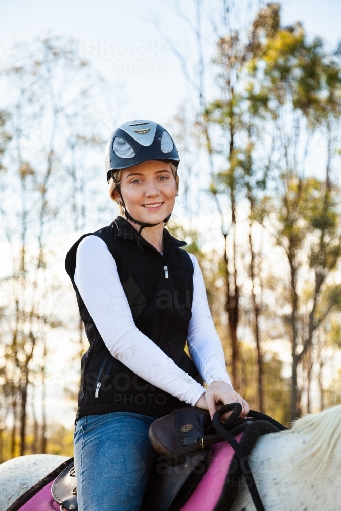Young female rider on her horse wearing a riding helmet for safety - Australian Stock Image