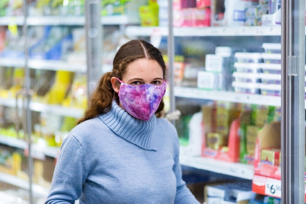 Image of Young female shopper walking down grocery store aisle wearing