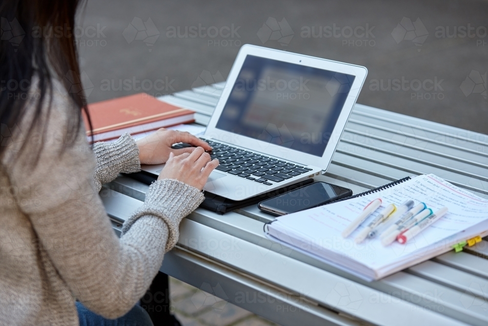 Image of Young female student studying on her laptop outdoors ...